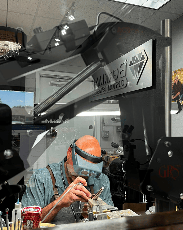 Man wearing a mask and goggles, working on a machine in a workshop
